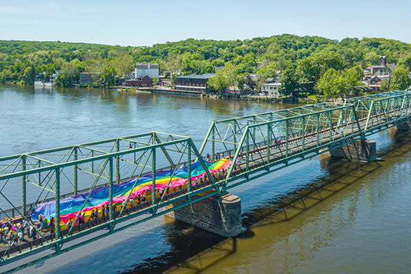 people marching on bridge carrying Pride Flag