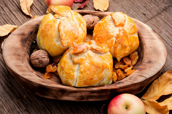 3 apple dumplings in wooden bowl with dried fruit and nuts