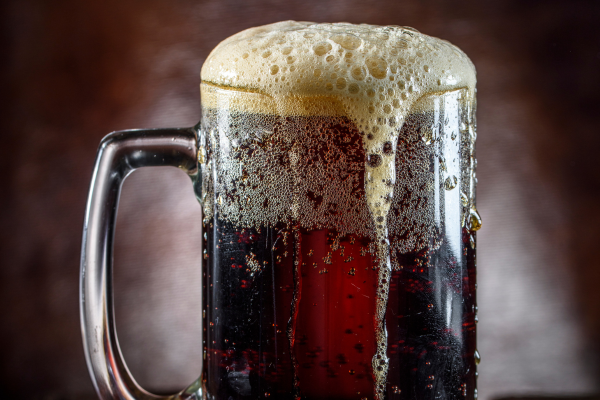 Glass mug of birch beer bubbling over