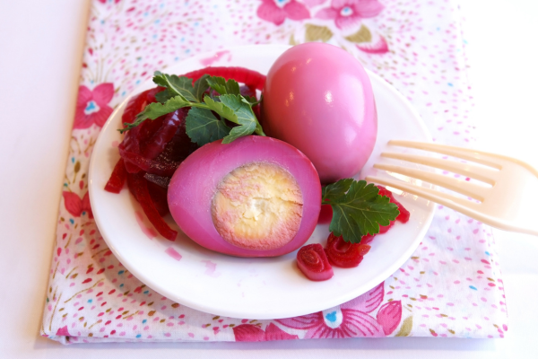 Red beet eggs on a plate garnished with parsley on floral napkin
