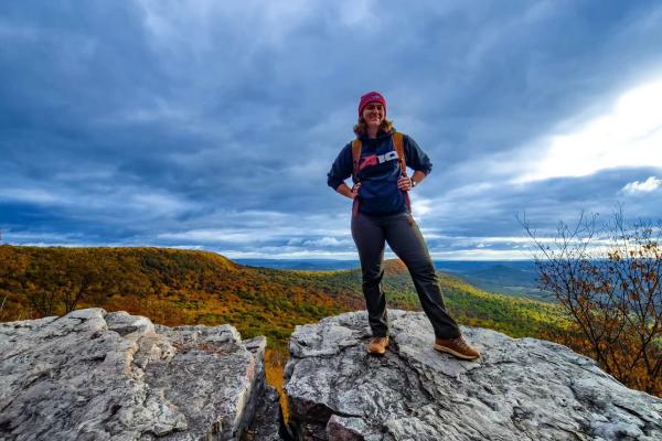 A young woman strikes a pose at HMS with colorful fall scenery behind her