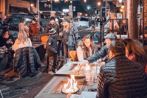 Small groups of people gather around fire pits for dining and fun at Chatty Monks on a winter's night.