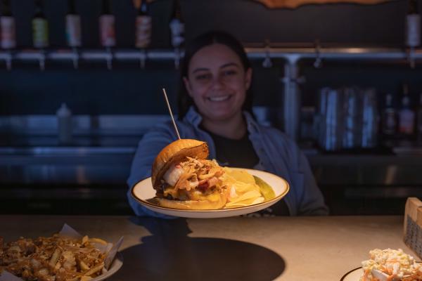 A burger is being served at the bar at saucony creek brewing with a side of fries in the background