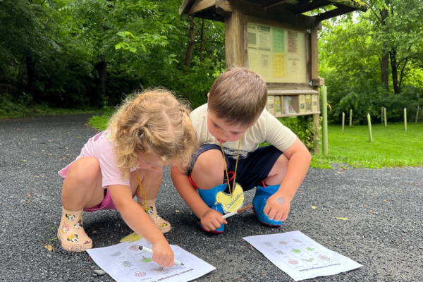 Two children outside in the park working on a scavenger hunt