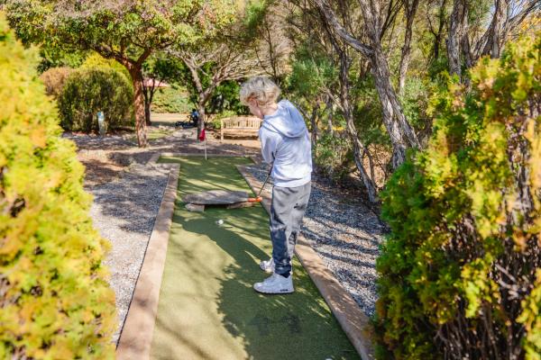 Boy putting a golf ball on the mini golf green at Amaze Miniature Park.