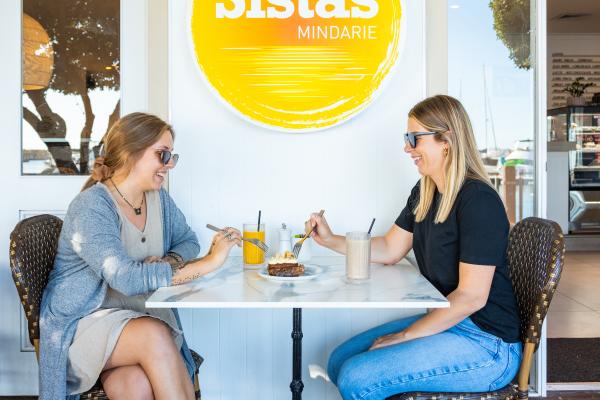 Two women enjoying a drink together alfresco style at Sistas Mindarie.