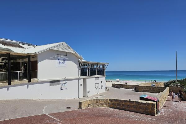 The exterior of Swell Mullaloo, with the beach and blue ocean in the distance.