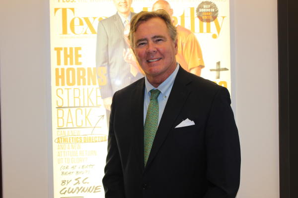 Headshot of David B. Dunham, wearing a suit in front of a projector showing Texas Monthly magazine.