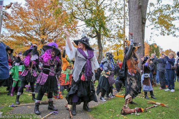 Group of witches dancing in front of autumn foliage