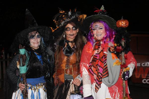 Three colorful witches posing in the dark.