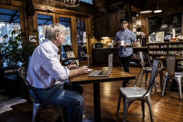 A man sits before his laptop, enjoying a cup of coffee at The Giddy Up Folsom.