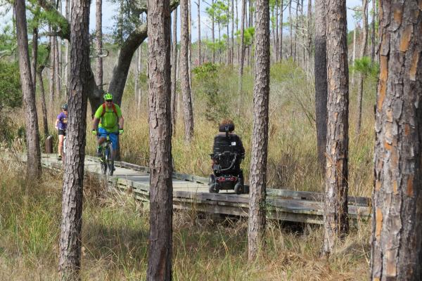People on bikes and wheelchairs on the Boy Scout Road Trail at Northlake Nature Center in St. Tammany