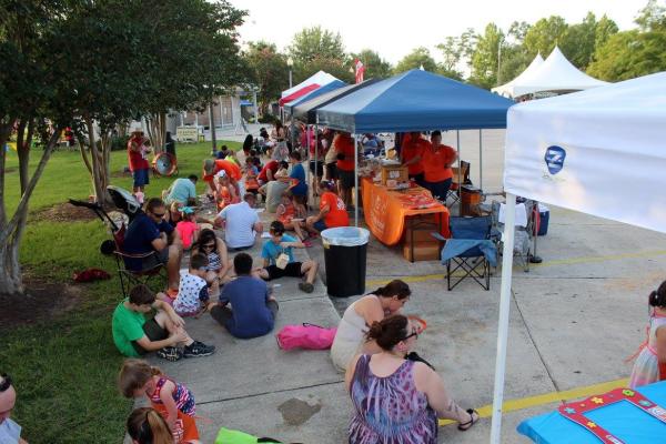 Kids' work on activities on a sidewalk lined with tents at Slidell Heritage Festival