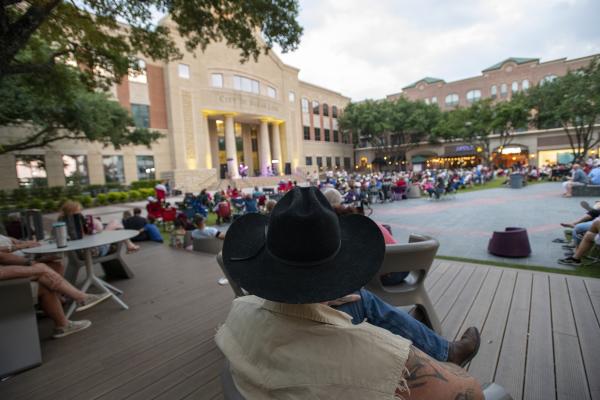 Man with cowboy hat at Sugar Land Town Square watching a concert