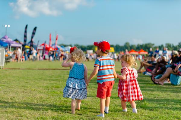 Three toddlers dressed in red, white and blue at Crown Festival Park at Sugar Land