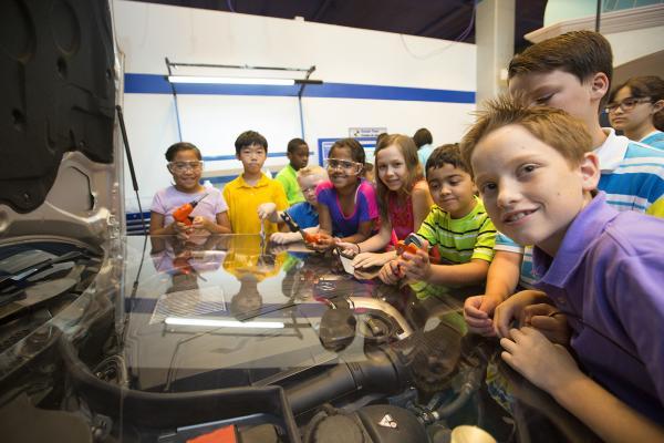 A group of children in the Kidtropolis exhibit at Fort Bend Children's Discovery Center learning about an automobile engine.