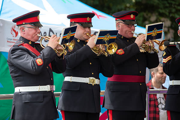 Servicemen in uniform playing brass instruments.