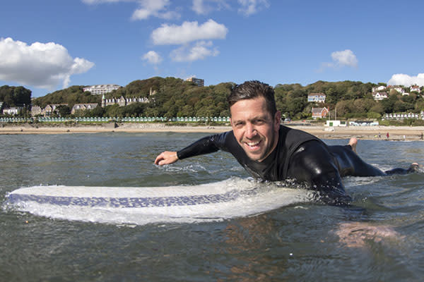 A man lying on a surfboard in the sea.