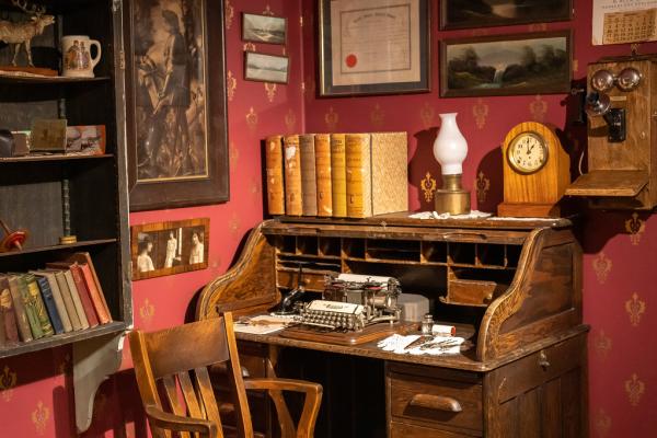 a museum exhibit of an early 20th century office, featuring a type-writer on a wooden desk