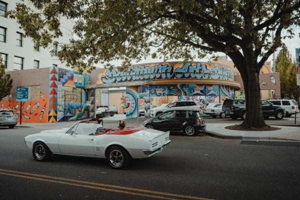 White convertible classic car driving down the muraled streets of Vancouver Washington