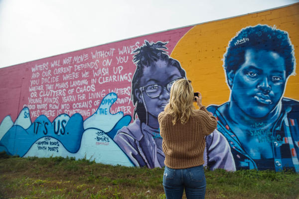 A woman taking a picture of a mural on a wall