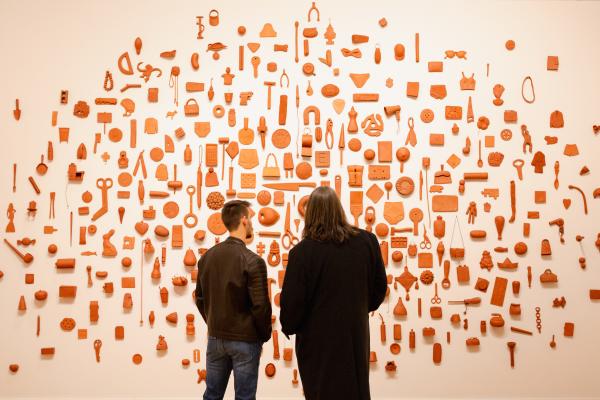 Two people looking at an art display on a wall