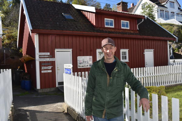 mann foran stakittgjerde og rødt hus
