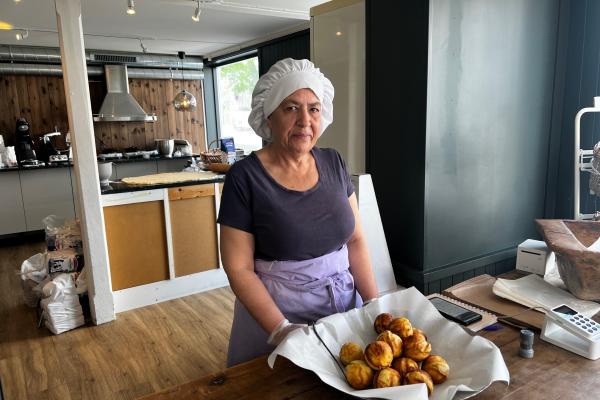 Dame på bakeri med et fat med munker foran seg