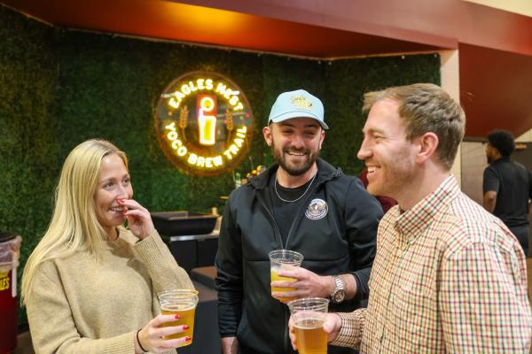 Two men and one woman drinking beer together and laughing