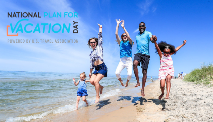 three adults and two children jump toward the blue sky on the shoreline of Lake Michigan. Text in upper left corner reads national plan for vacation day powered by u.s. travel association.