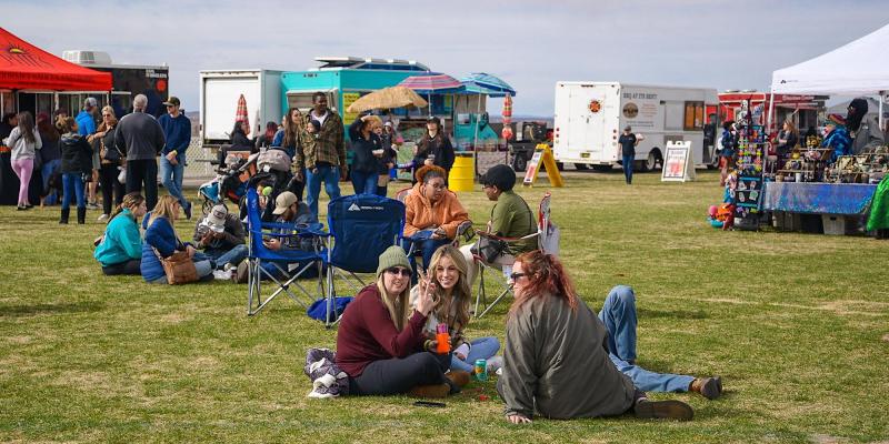 People sit on the grass enjoying the Great New Mexico Food Truck and Craft Beer Festival