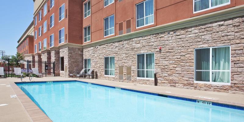 The Holiday Inn & Suites Oakland Airport pool surrounded by lounge chairs and sunshine.
