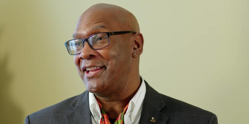 A portrait photo of a Black man in the middle of a speech