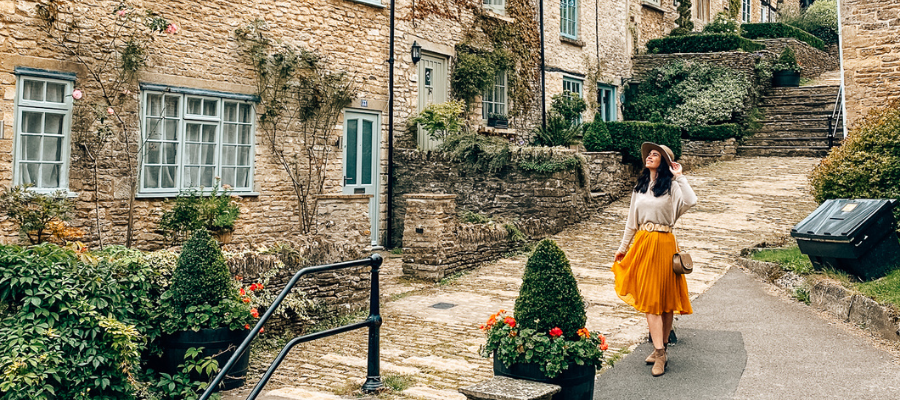 A lady in an orange skirt and a white top walking along the small street in Tetbury.