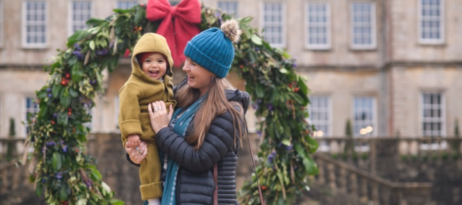 Toddler and mum standing in front of a giant wreath at Dyrham park
