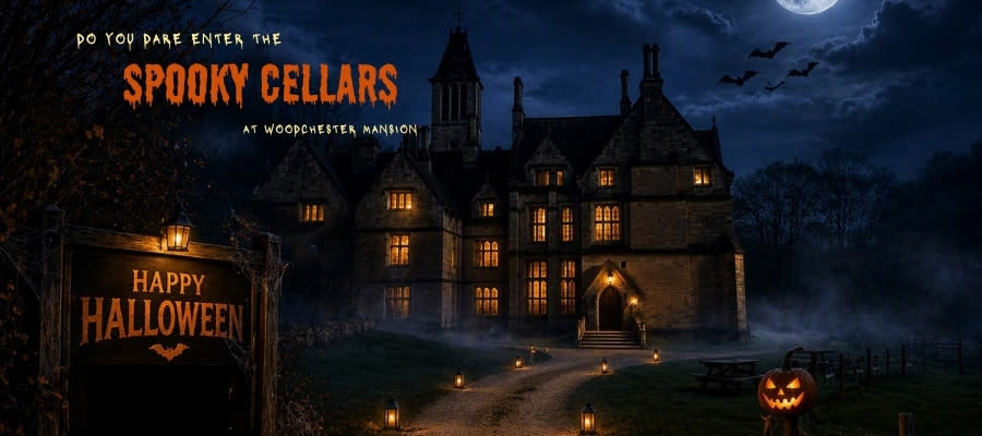 The Gothic Woodchester Mansion in the Cotswolds lit up at night by warm orange lights with a full moon above