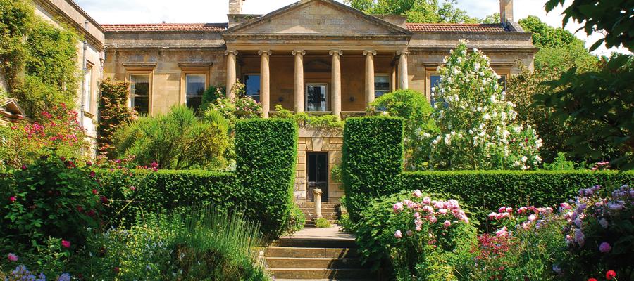 The impressive house at Kiftsgate Court Gardens surrounded by topiary trees and flowering shrubs and