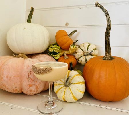 A photo of one of Egg's special fall cocktails in front of a group of pumpkins.
