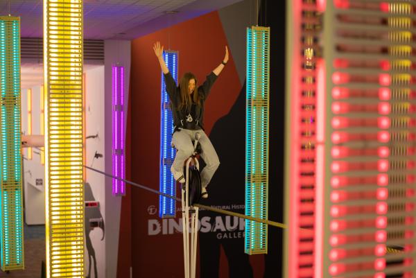 Woman riding high-wire unicycle at COSI