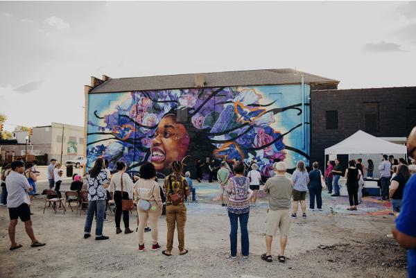People standing in front of Free to Be, a mural by Sarah Eberly
