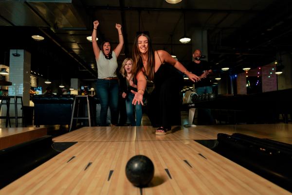 A group of friends celebrating on a duckpin bowling lane at PINS Mechanical