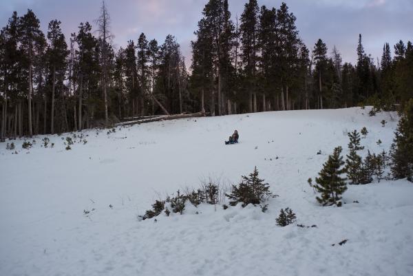two people sledding down hill in forest