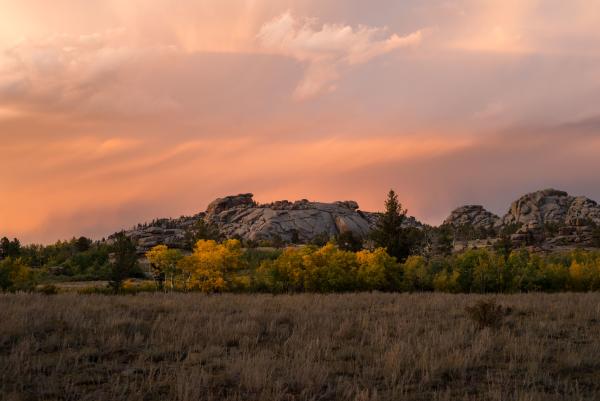 sunset on golden aspens in front of large granite rock formation