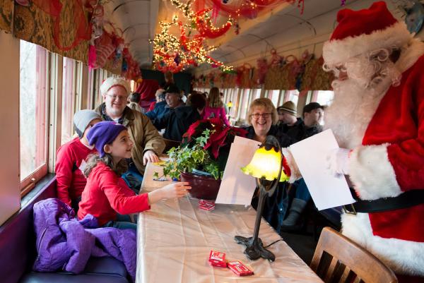 Santa giving coloring books to children on the decorated train