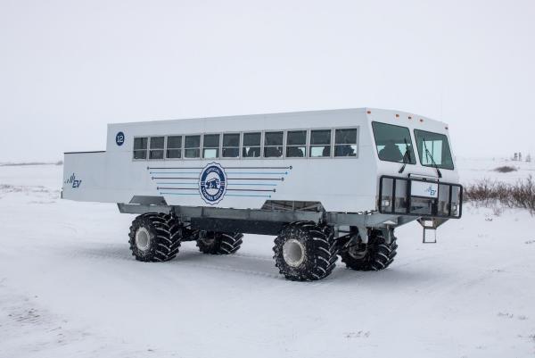 A white Tundra Buggy sits in the snow.