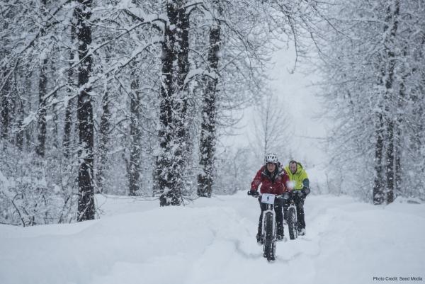 two fat bikers ride in snow through a Valdez forest