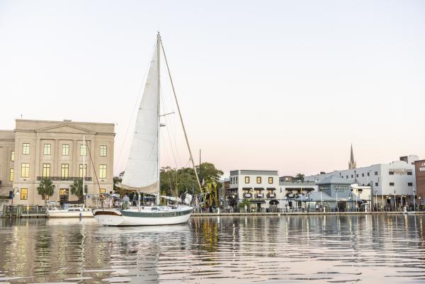 Sailboat on the river in front of downtown Wilmington's skyline.