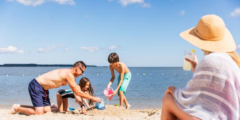Family playing in sand while mom watches on Yorktown Beach