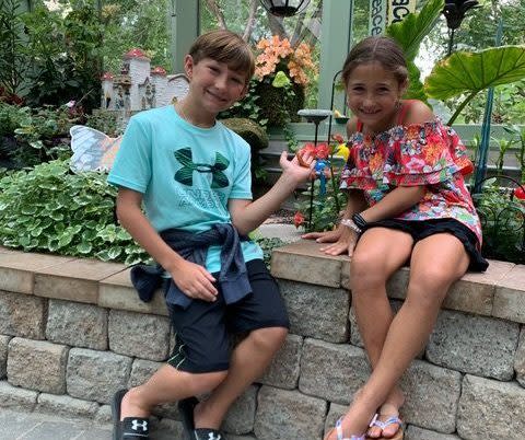 Two kids have a close up encounter with butterflies at the Wings of Mackinac conservatory on Mackinac Island.