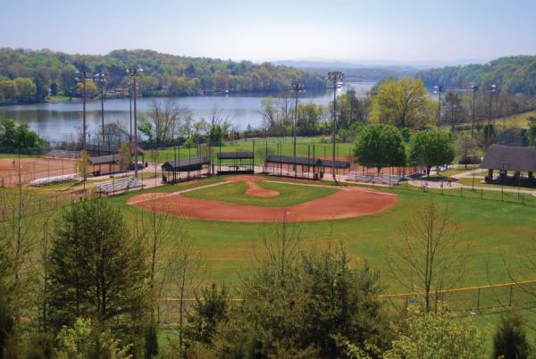 The Tennessee River flows gently by the red baseball diamond at Knoxville's Lakeshore Park.